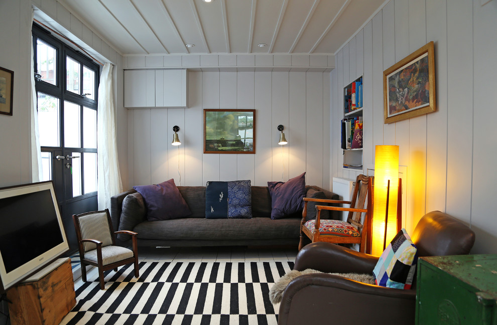 Стильный дизайн: гостиная комната в морском стиле с белыми стенами, отдельно стоящим телевизором и деревянным полом - последний тренд