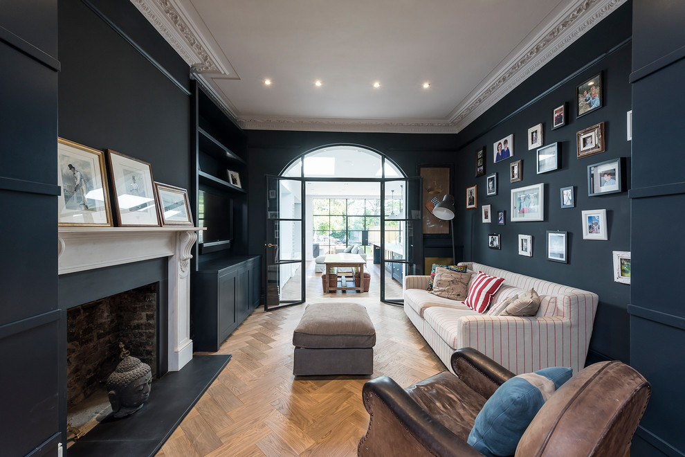 Imagen de sala de estar cerrada clásica renovada con paredes azules, suelo de madera en tonos medios, todas las chimeneas, televisor colgado en la pared y suelo marrón