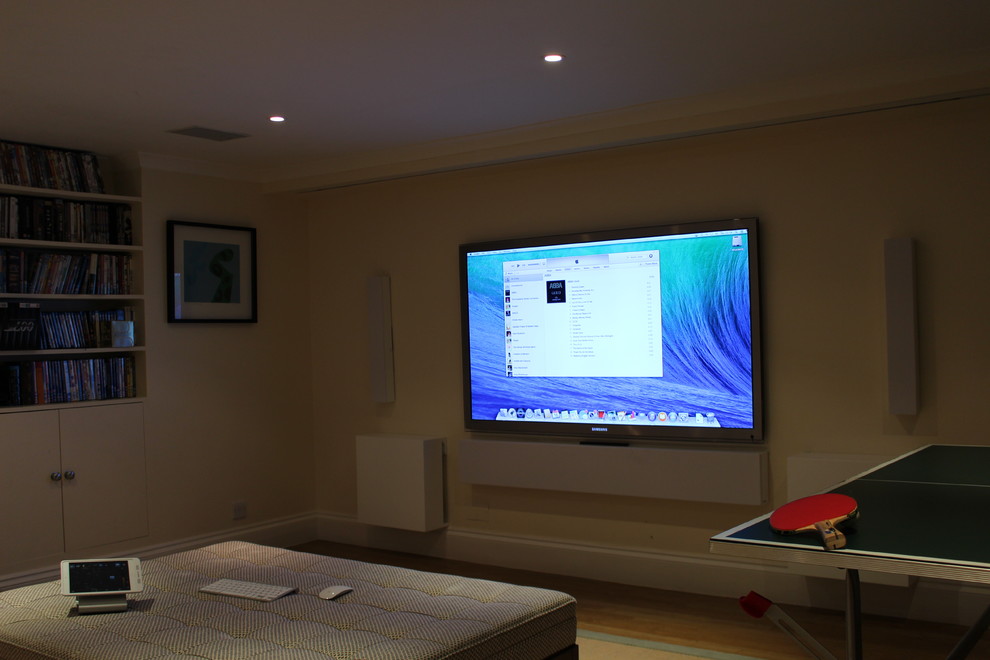 Example of a large classic enclosed light wood floor game room design in London with beige walls, no fireplace and a wall-mounted tv
