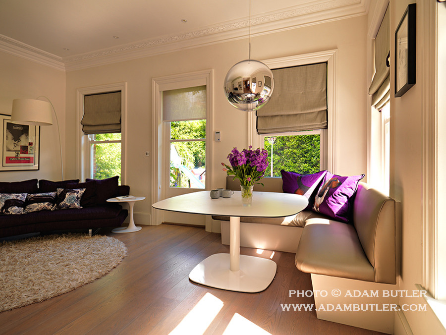 Exemple d'une salle de séjour tendance de taille moyenne et ouverte avec un mur blanc, un sol en bois brun et un téléviseur encastré.