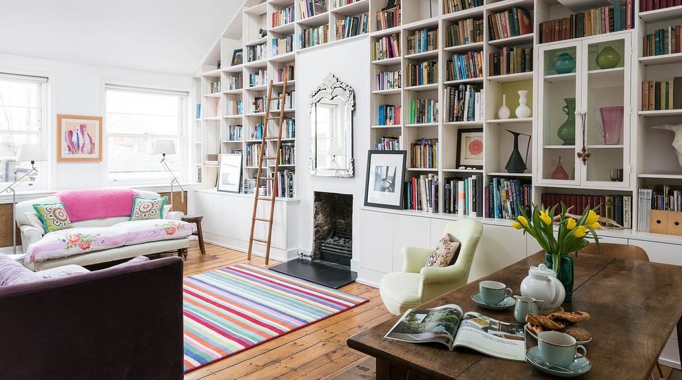 Idee per un soggiorno bohémian aperto con libreria, pareti bianche, pavimento in legno massello medio, camino classico e nessuna TV