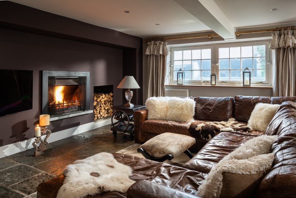 Photo of a large rural enclosed games room in Cornwall with brown walls, a wall mounted tv, grey floors, a standard fireplace and a feature wall.