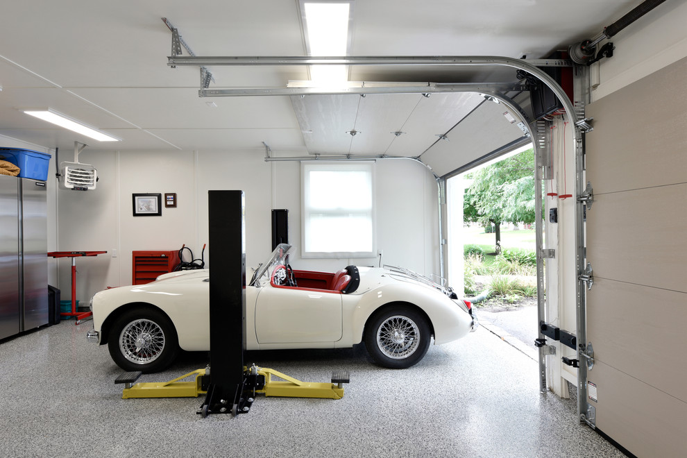 На фото: большой пристроенный гараж в стиле лофт с мастерской для двух машин с