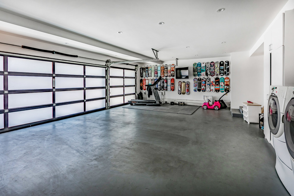 На фото: большой пристроенный гараж в стиле модернизм с мастерской для трех машин