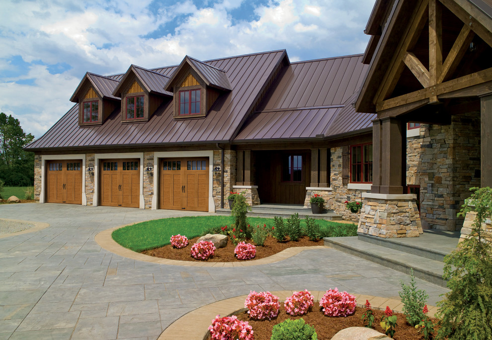 Example of a large mountain style attached three-car garage design in Cincinnati