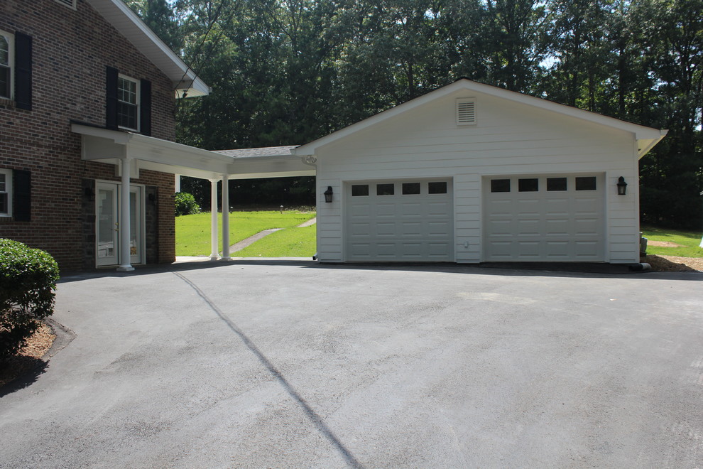 На фото: большой отдельно стоящий гараж в классическом стиле с навесом для автомобилей для двух машин