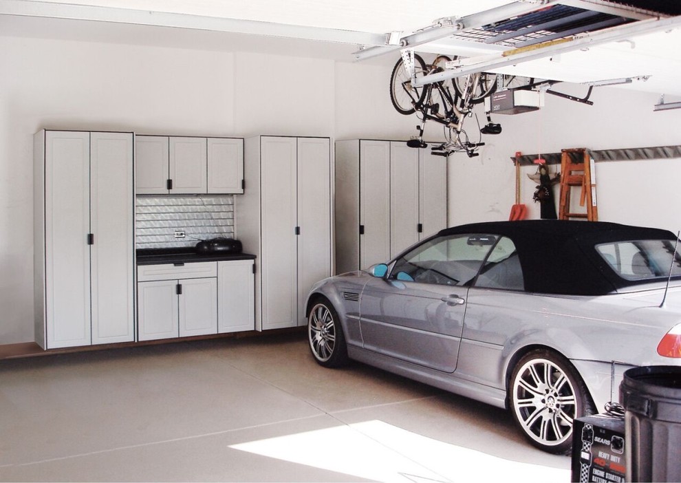 На фото: большой гараж в стиле неоклассика (современная классика) с мастерской для двух машин с