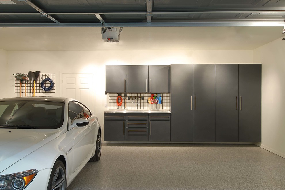Exemple d'un très grand garage pour trois voitures attenant moderne avec un bureau, studio ou atelier.