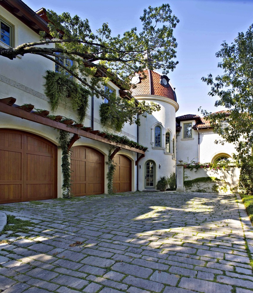 Example of a large tuscan attached three-car garage design in Dallas