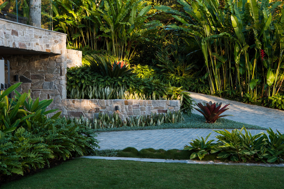 Immagine di un grande giardino tropicale esposto in pieno sole davanti casa in primavera con pavimentazioni in pietra naturale