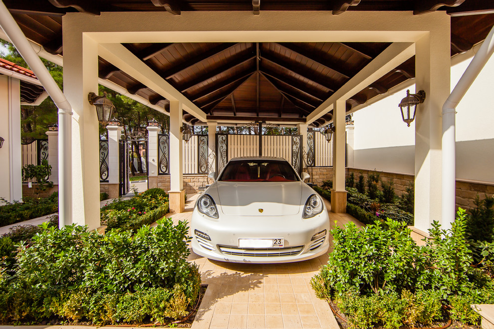 На фото: отдельно стоящий гараж в средиземноморском стиле с навесом для автомобилей с