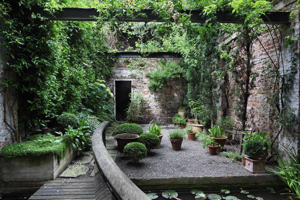 Inspiration for an industrial courtyard garden in London with gravel and a potted garden.