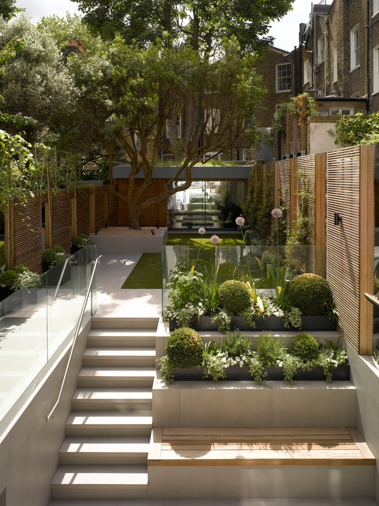 Halbschattiger Moderner Garten mit Kübelpflanzen und Betonboden in London