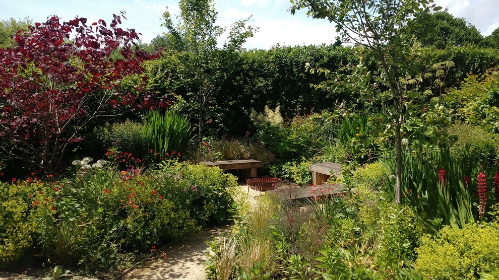 Modelo de jardín clásico de tamaño medio en verano en patio lateral con brasero, exposición parcial al sol y gravilla