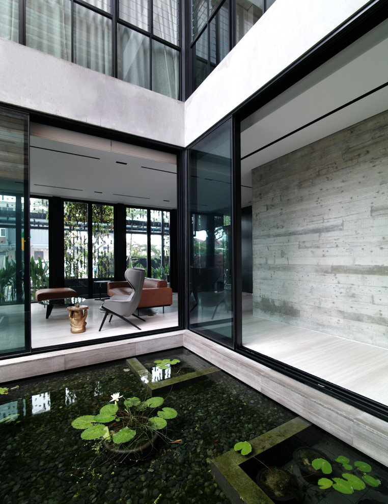Halbschattiger Moderner Garten im Innenhof mit Wasserspiel und Betonboden in Singapur