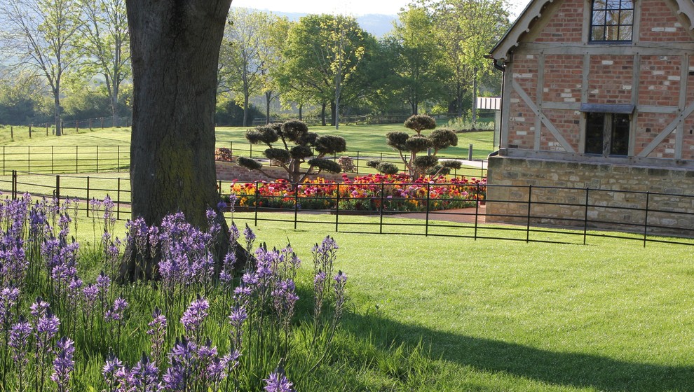 Exemple d'un très grand jardin arrière tendance l'été avec un massif de fleurs et des pavés en pierre naturelle.