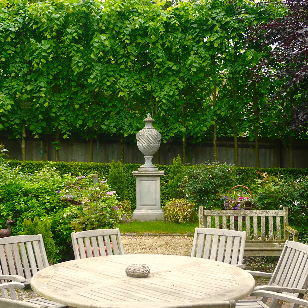Diseño de jardín clásico en patio trasero con jardín francés, exposición parcial al sol y adoquines de piedra natural