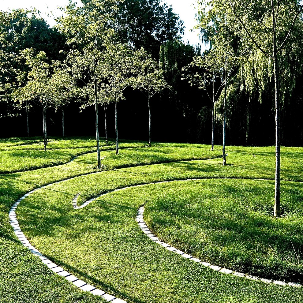 Réalisation d'un très grand jardin arrière champêtre avec une exposition ensoleillée et des pavés en pierre naturelle.