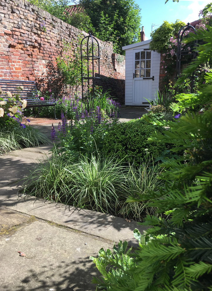 Immagine di un piccolo giardino formale classico esposto a mezz'ombra in cortile con pavimentazioni in pietra naturale