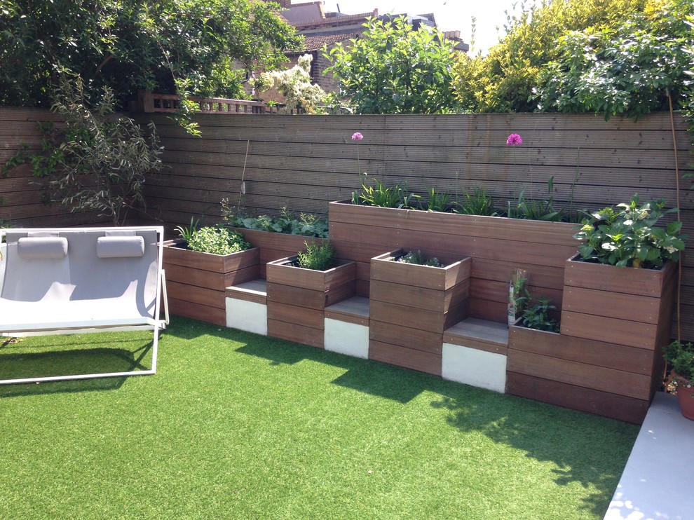 This is an example of a small modern back formal full sun garden for summer in London with a living wall and decking.