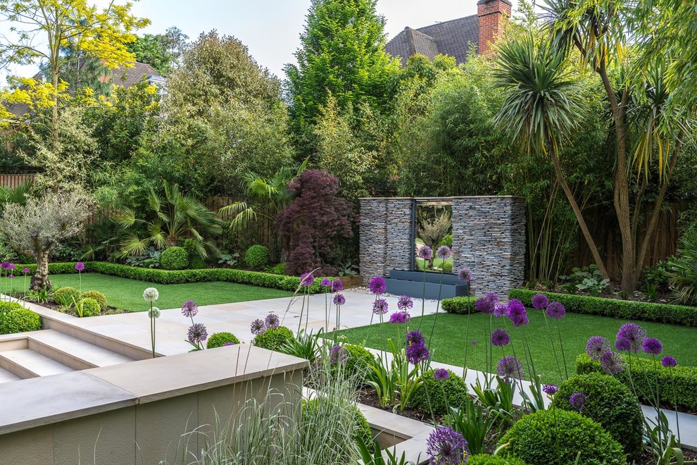 Foto de jardín tropical grande en patio trasero con jardín francés, fuente y adoquines de piedra natural