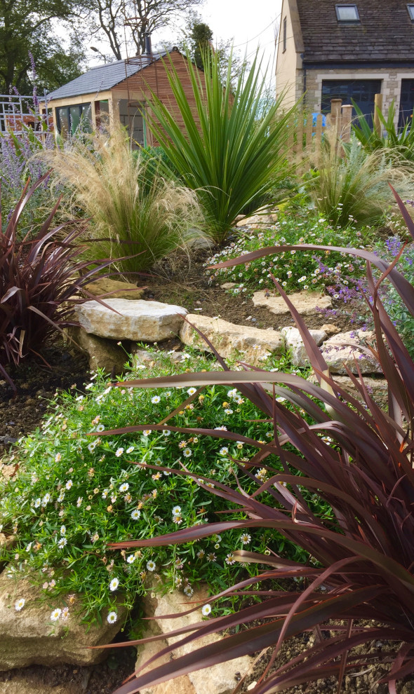 Esempio di un grande giardino xeriscape minimal esposto in pieno sole in estate con sassi e rocce e un pendio, una collina o una riva