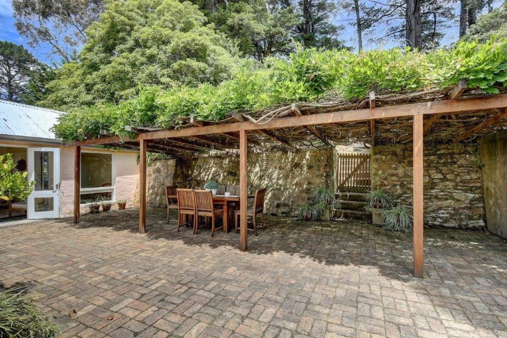 Imagen de jardín de secano campestre de tamaño medio en primavera en patio con muro de contención, exposición parcial al sol y adoquines de piedra natural