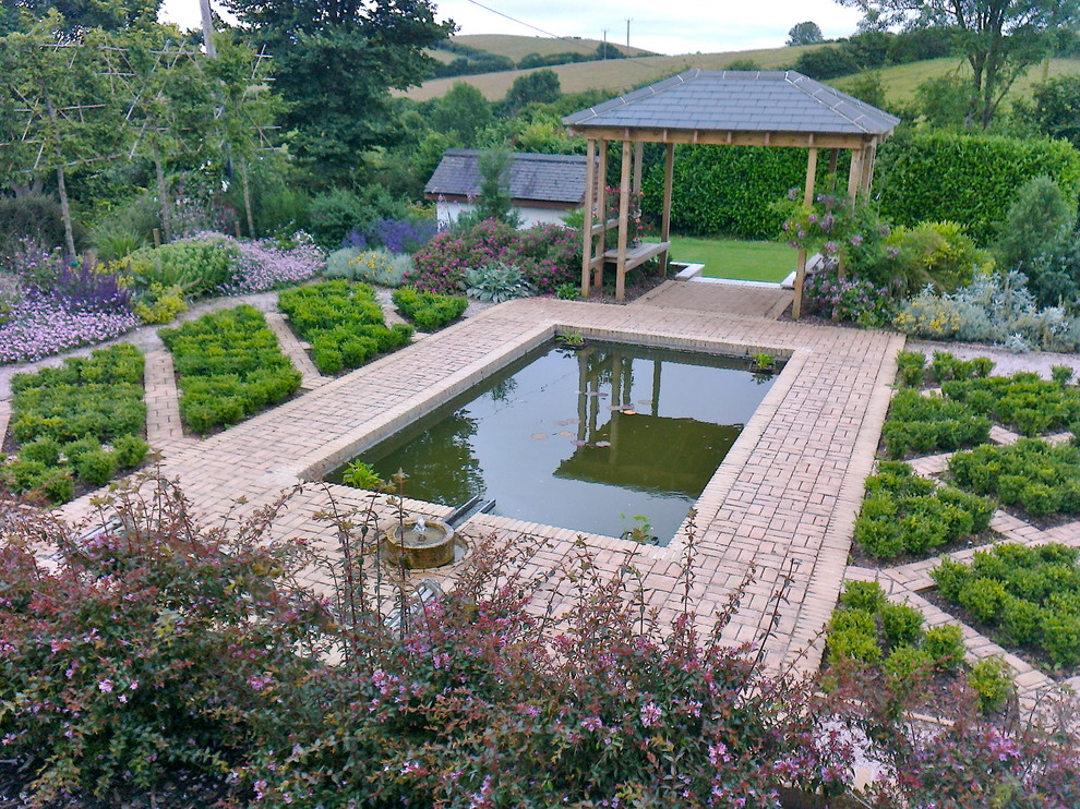 Inspiration for a mediterranean front full sun raised pond for summer in Devon with a water feature and brick paving.