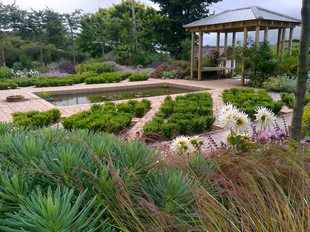 Photo of a mediterranean front full sun raised pond for summer in Devon with a water feature and brick paving.