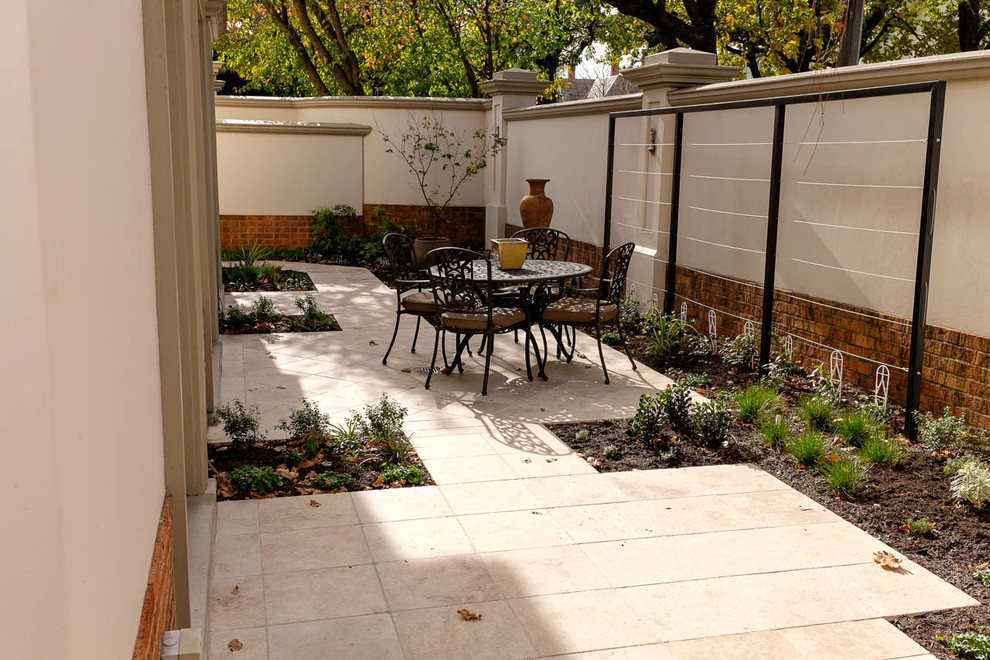 Ejemplo de jardín actual de tamaño medio en primavera en patio con exposición parcial al sol y adoquines de piedra natural