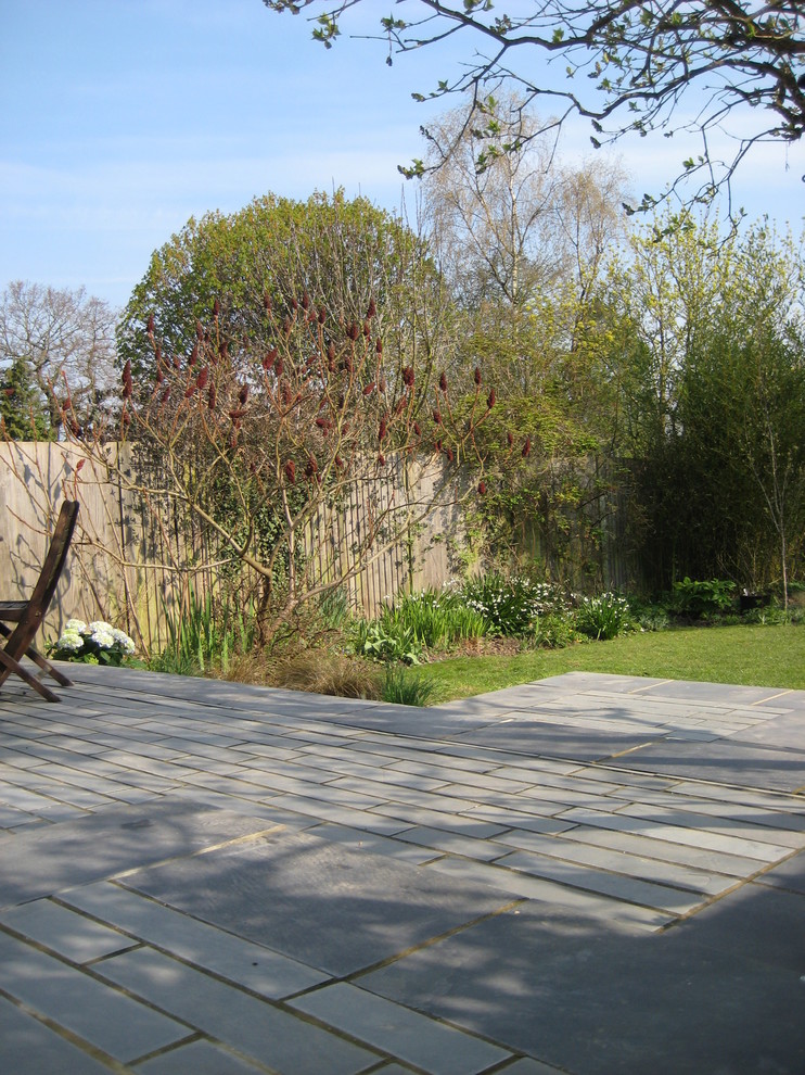 Ejemplo de jardín vintage de tamaño medio en patio trasero con exposición reducida al sol y adoquines de piedra natural