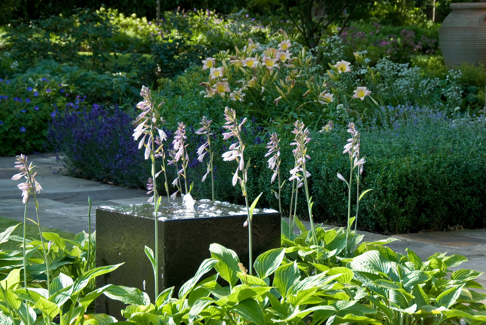 Idées déco pour un grand jardin arrière victorien l'été avec une exposition partiellement ombragée et des pavés en pierre naturelle.
