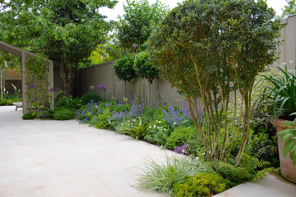 Photo of a medium sized classic back formal partial sun garden for spring in London with natural stone paving.