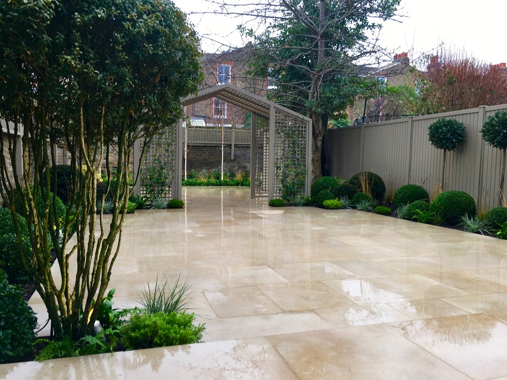 Design ideas for a medium sized classic back formal partial sun garden for spring in London with natural stone paving.