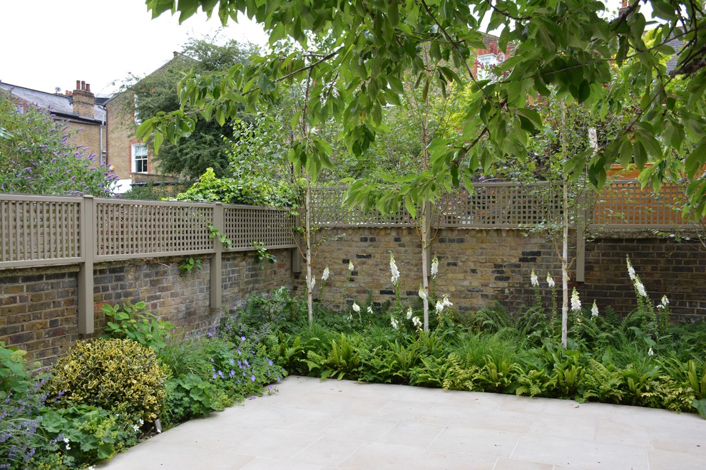 This is an example of a medium sized classic back formal partial sun garden for spring in London with natural stone paving.