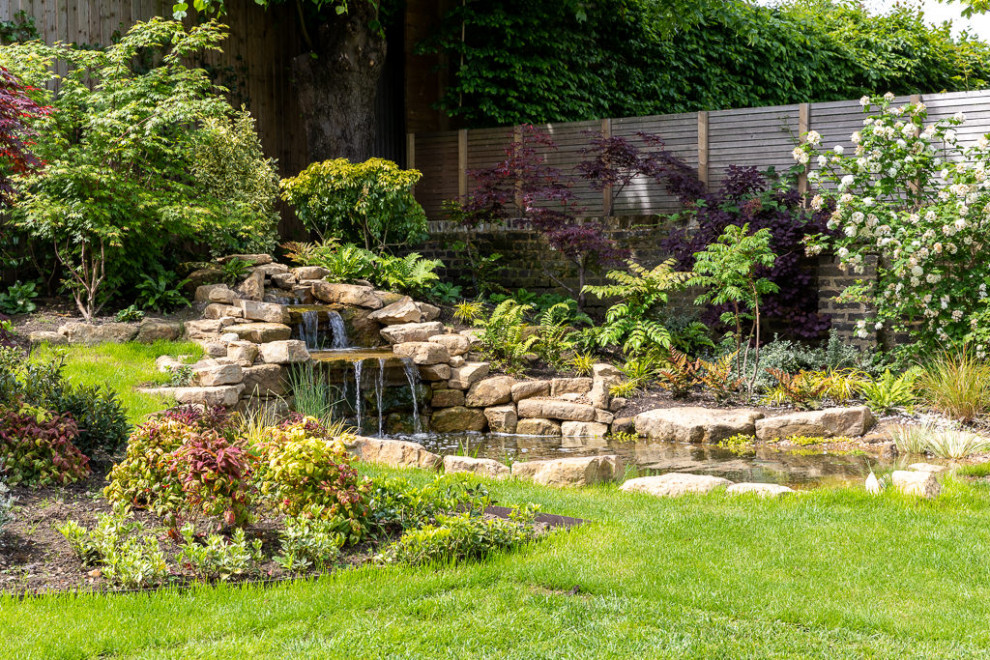 Ispirazione per un giardino classico esposto a mezz'ombra di medie dimensioni e dietro casa con una cascata