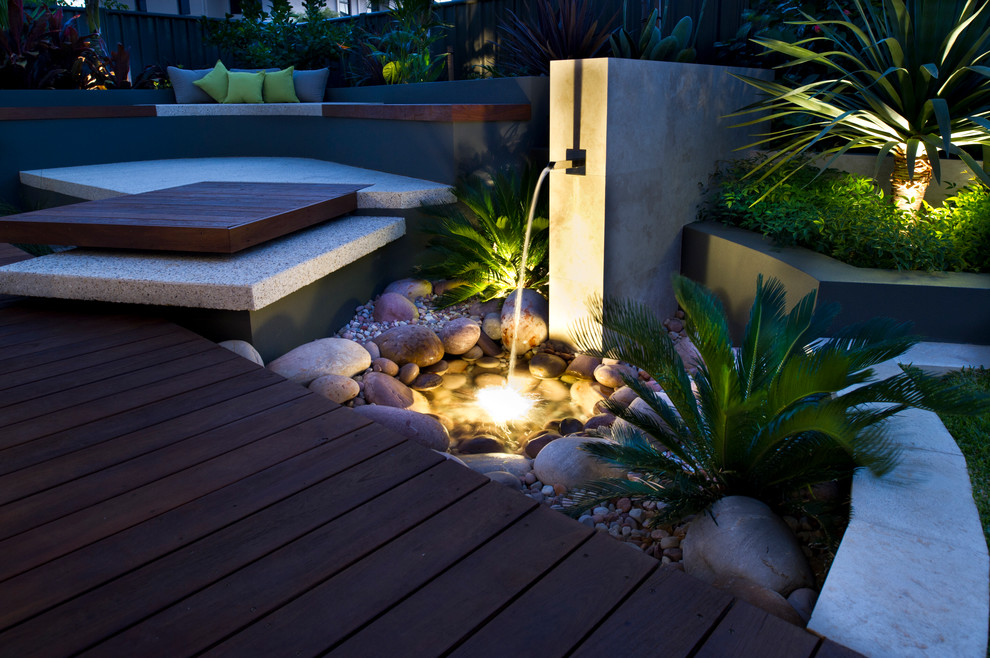 На фото: маленький солнечный садовый фонтан на заднем дворе в современном стиле с настилом и хорошей освещенностью для на участке и в саду с