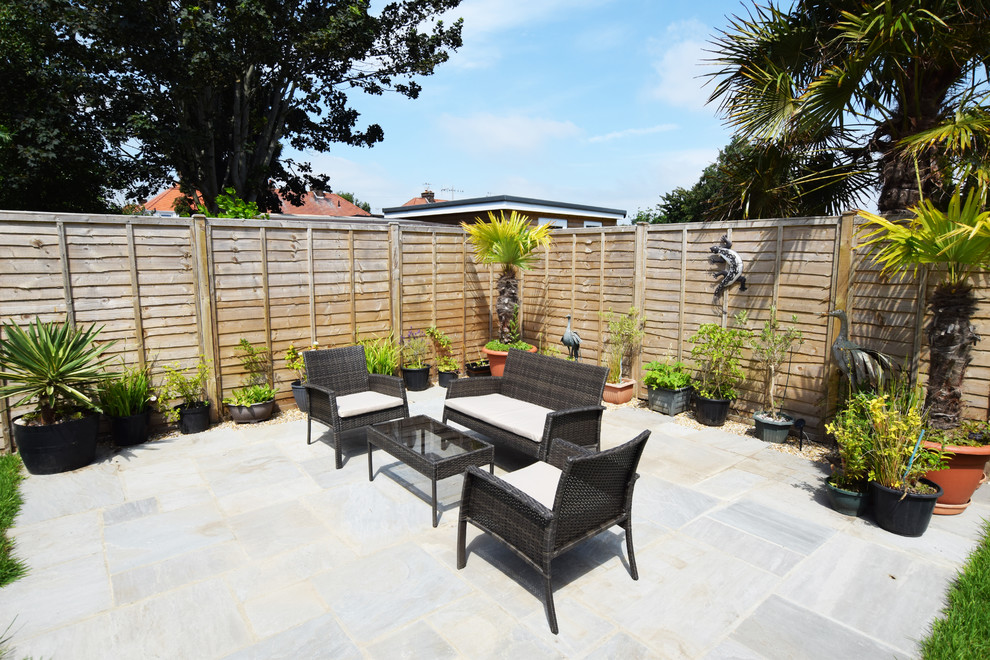 Design ideas for a large traditional back patio in Sussex with a potted garden and concrete paving.