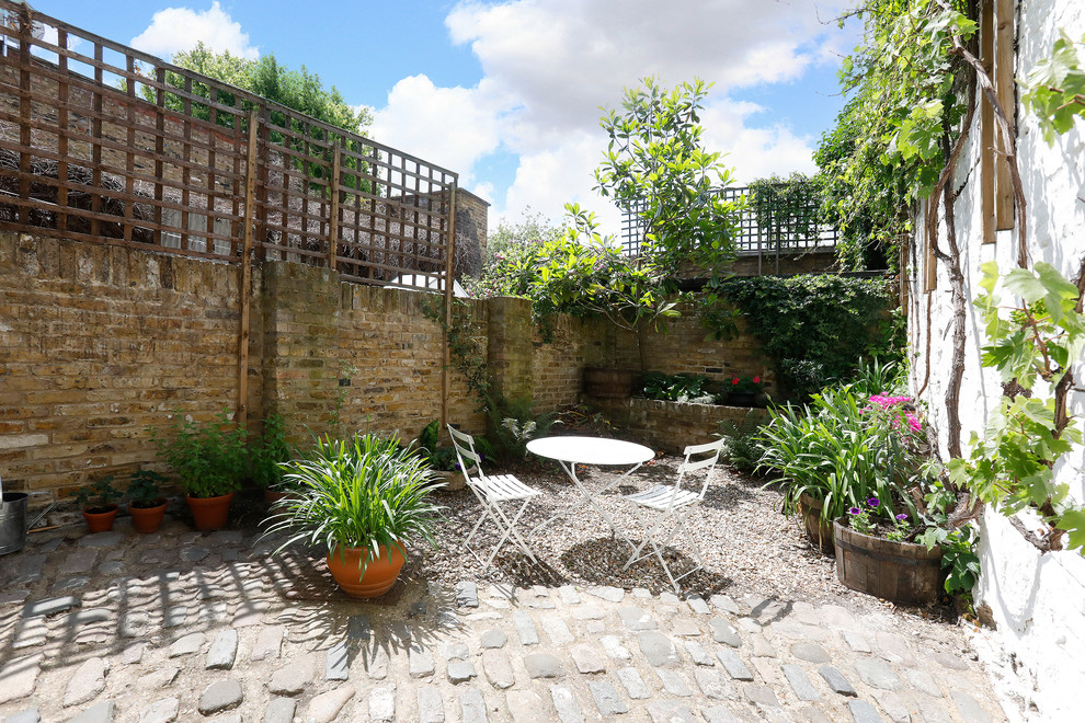 Immagine di un piccolo giardino design esposto a mezz'ombra dietro casa in estate con un muro di contenimento e ghiaia