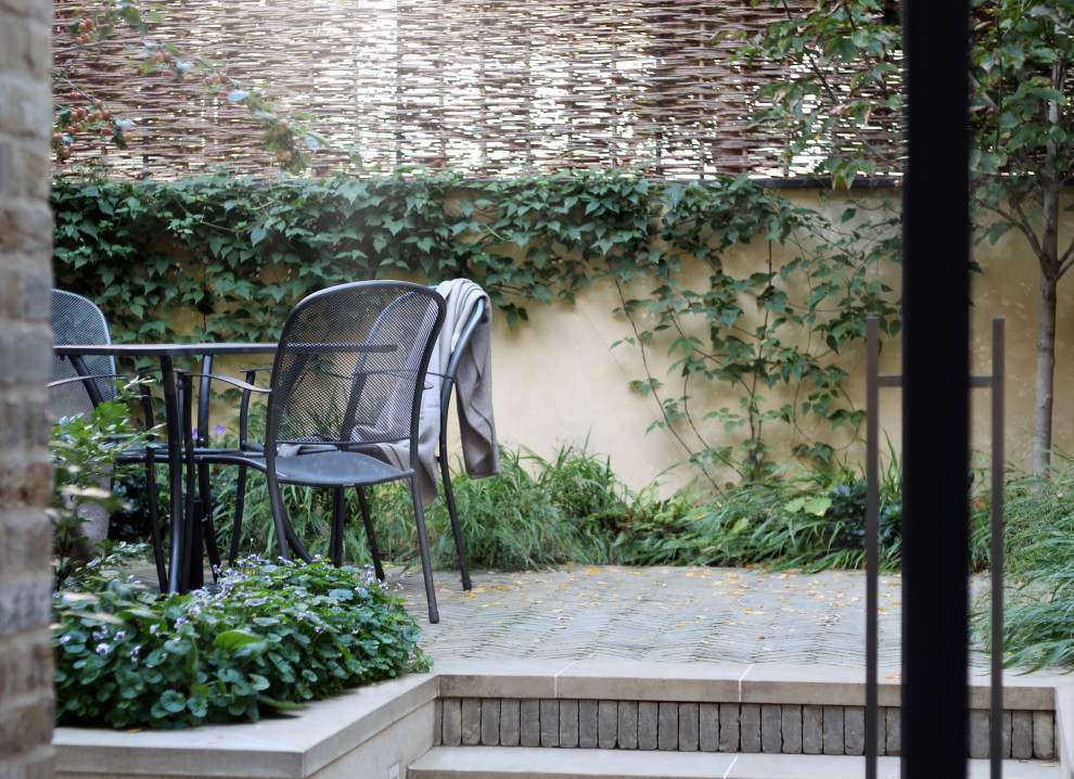 Imagen de jardín actual pequeño en otoño en patio con jardín francés, privacidad, exposición parcial al sol y adoquines de ladrillo
