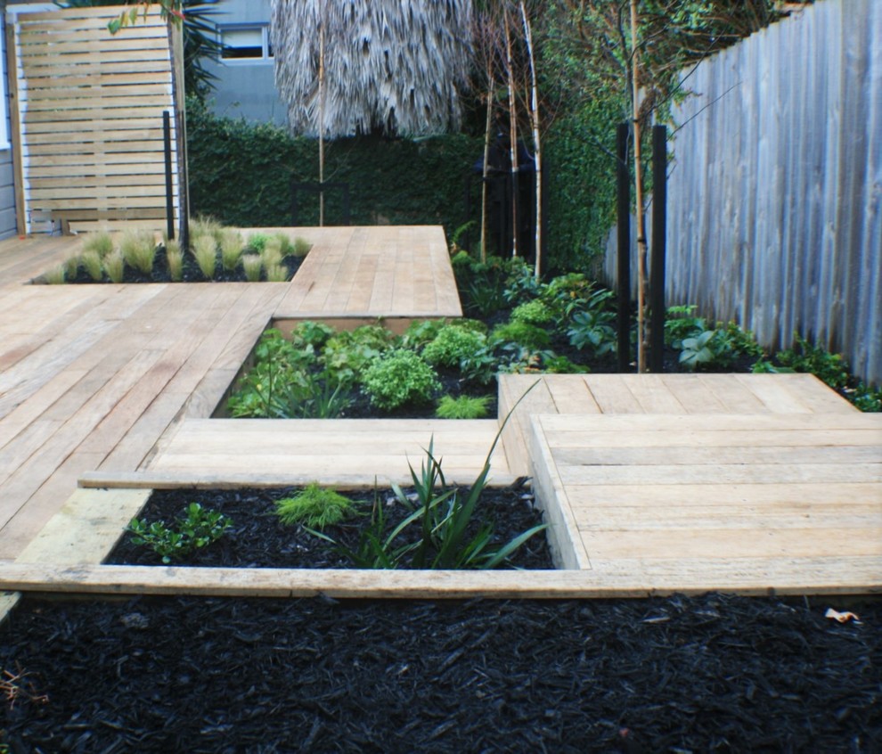 Aménagement d'un petit jardin arrière contemporain l'été avec une exposition partiellement ombragée et une terrasse en bois.