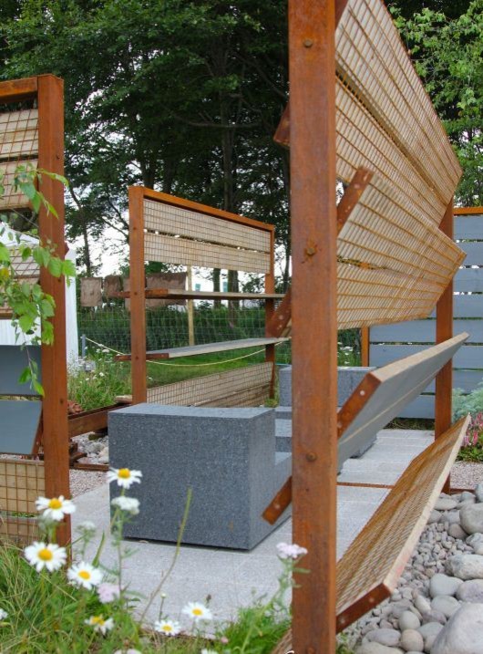 Inspiration för små rustika trädgårdar, med en stödmur och naturstensplattor