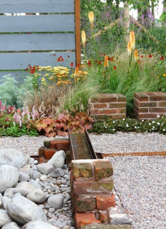 Design ideas for a small rustic back formal garden in Manchester with a water feature and gravel.