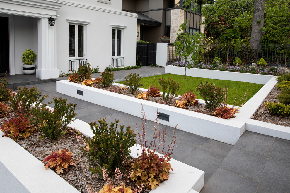 Large contemporary front full sun garden for summer in Melbourne with natural stone paving.