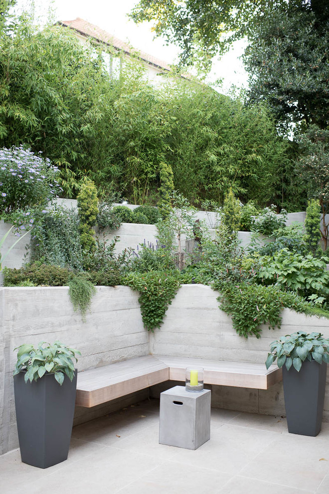 Imagen de jardín minimalista de tamaño medio en verano en patio trasero con jardín francés, muro de contención, exposición parcial al sol y adoquines de hormigón