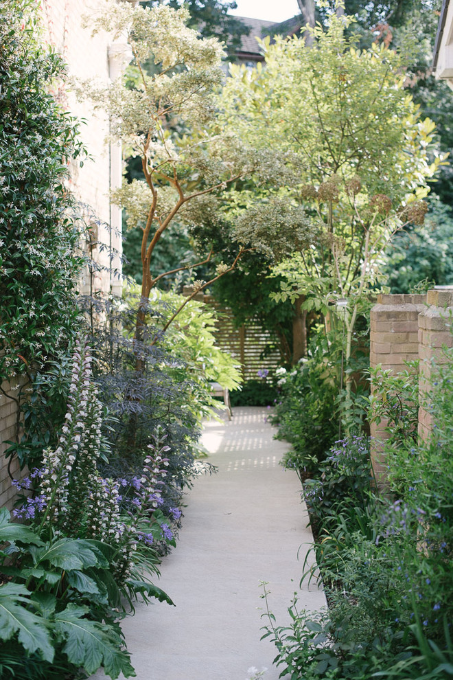 Inspiration för en mellanstor funkis formell trädgård i delvis sol i slänt på sommaren, med en stödmur och marksten i betong