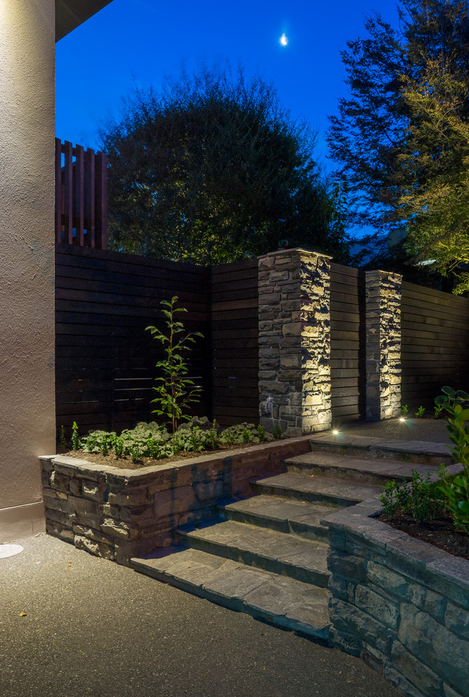 Inspiration för en liten funkis formell trädgård framför huset, med en stödmur och naturstensplattor