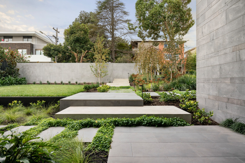 Foto di un giardino minimal esposto in pieno sole con un muro di contenimento