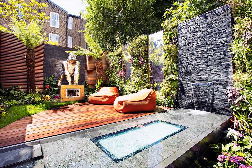 This is an example of a world-inspired back formal garden in London with a water feature and decking.
