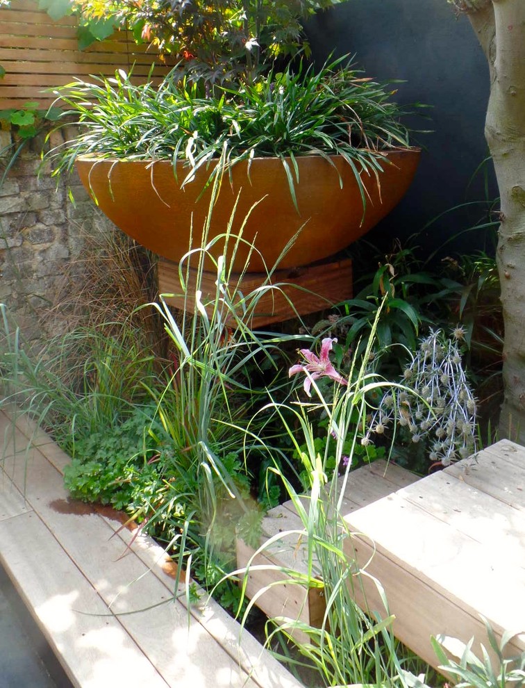 Inspiration for a small eclectic back formal partial sun garden for summer in London with a potted garden and decking.